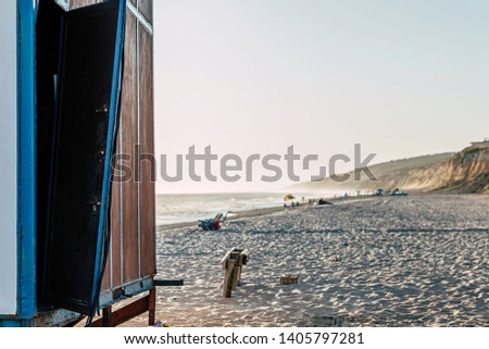 Beach house with broken door, showing an open toilet or chiringuito, sea and blue sky background