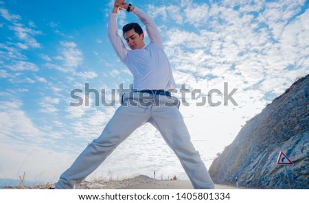 Fit male stretching and performing his morning routines while wearing a white shirt, practicing early in the morning on a cold winter day