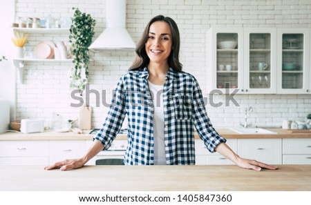 Young beautiful modern woman stands near table on kitchen at home. Royalty-Free Stock Photo #1405847360