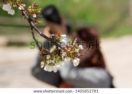 A girl practices with her camera in front of a tree. (Horizontal)