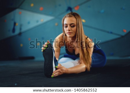 Stretching gymnast girl doing warming exercizes. View of attractive young woman doing sports at gym