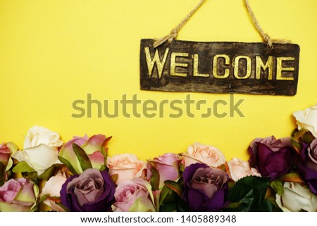 welcome sign with rose flower on yellow background
