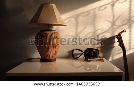  Lamp and camera on the table with shadow wall background                              