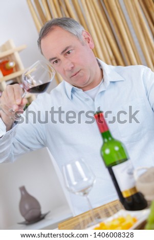 A middle-age man tasting wine