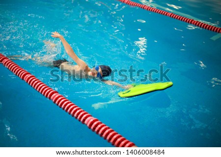 Swimming lessons for kids in sport school, little boy practising swimming in the pool