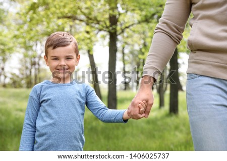 Happy little child holding hands with his father in park. Family time