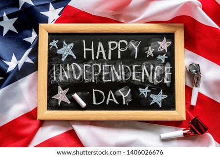 Independence Day USA concept. Memorial Day. Chalkboard with text Happy Independence Day decorated with noisemakers on USA flag background