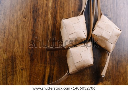 Ketupat (Rice Dumpling) On wooden texture Background. Ketupat is a natural rice casing made from young coconut leaves for cooking rice during eid Mubarak. selective focus - Image