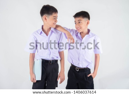 Little Asian sibling boys in student uniform pose together on white background