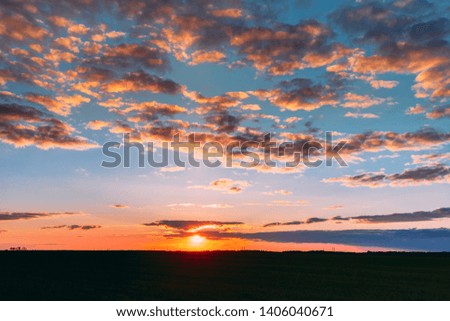 Natural Sunset Sunrise Over Field Meadow. Bright Dramatic Sky And Dark Ground. Countryside Landscape Under Scenic Colorful Sky At Sunset Dawn Sunrise. Skyline, Horizon. Warm Colours.