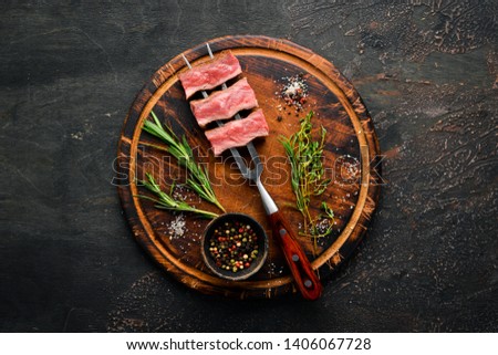 Juicy Steak on the fork with herbs and spices. Top view. Free space for your text.