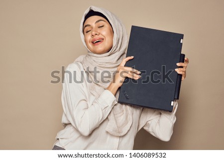 joyful islam woman with laptop on beige background                