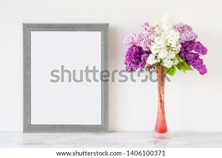 Fresh branches of light pink, purple, white lilac blossoms in vase on table at gray wall. Empty place for inspirational, emotional, sentimental text, lovely quote or sayings in frame. Front view.