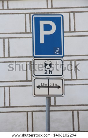 two hour maximum parking sign with disabled icon against an elaborately painted wall
