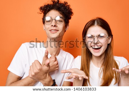 Happy red-haired woman in glasses and curly guy on an orange background                  