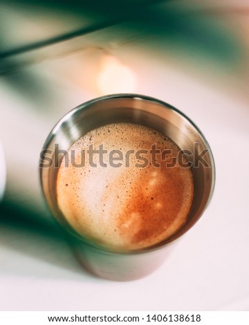 Close up of Espresso coffee with latte art taken through the leaves of a house plant. Bokeh Coffee style photo