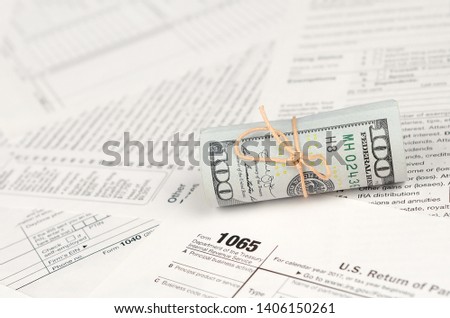 1065 U.S. Return of Parentship Income form with roll of american dollar banknotes