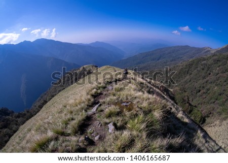 An unidentified woman descending on a mountain ridge from High Camp(Kew) along the Mardi Himal Trek.