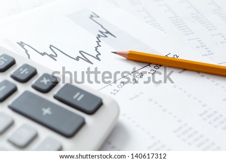 Close up of business stationery: calculator, graphs, pencil