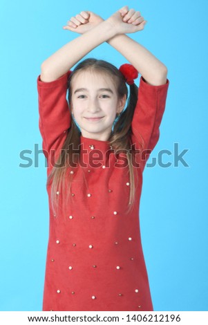 Full length studio photo girl wearing red dress standing on blue background.