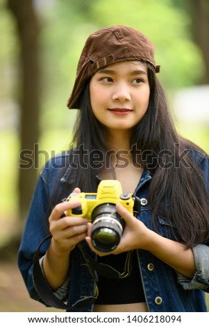 Portrait of beautiful young Asian  woman with camera at summer green park 