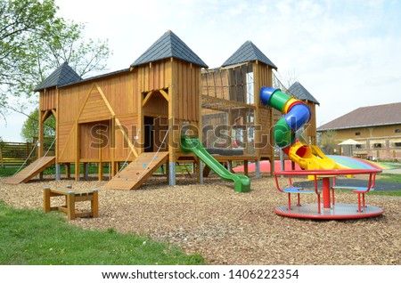 An empty playground wooden castle   playground with slides, merry-go-round, roundabout, and many other playing equipment and activities for small and bigger children.  Royalty-Free Stock Photo #1406222354