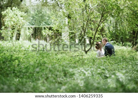 The groom in a suit and the bride in a wedding dress are walking in the park. A young couple walking in the park