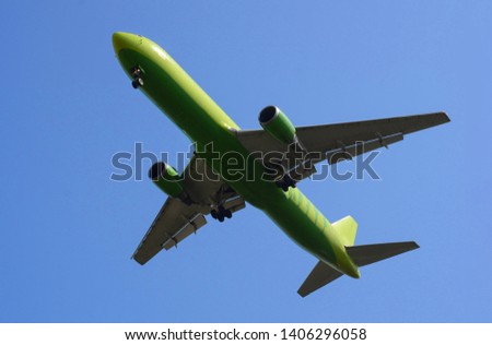 Image of a beautiful green airplane flying through the blue sky close up