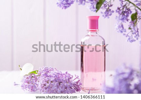 pink perfume bottle with lilac flowers on white background
