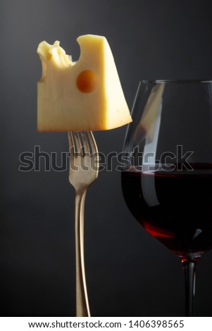  Maasdam cheese with red wine on a black background. Copy space.
