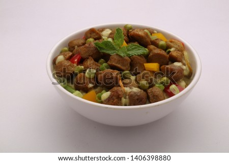 soya chunks masala-beautifully garnished soya chunks green chilli , green peas , red capsicum in a white bowl with white background