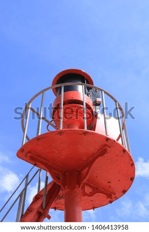A coastal viewing platform with a warning light for shipping. Painted a bright coastal red against a deep blue summer sky. Could be used as a coastal home interior picture.