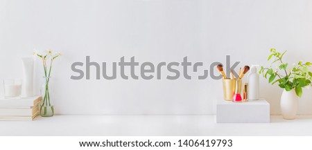 Home interior with decor elements. White daffodils in a vase, branches with green leaves, cosmetic set Royalty-Free Stock Photo #1406419793
