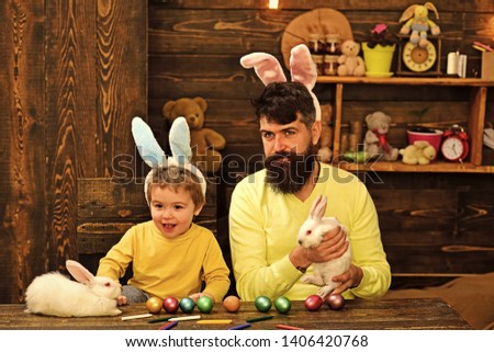 Child and father holding basket with painted eggs. Rabbit's family with bunny ears. Cute little child boy wearing on Easter day.