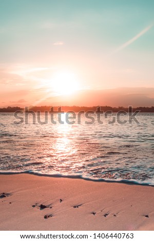 Orange teal sunset on a beautiful beach in Gili Trawangan, Lombok. Beautiful vivid sunset over beach with ocean water. A beach scene with sunset in the background. Royalty-Free Stock Photo #1406440763