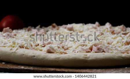 Close up for chef hands in transparent gloves touching unbaked pizza on black background, cooking concept. Frame. Man in cooking gloves preparing pizza for baking.