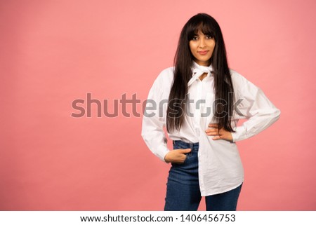 Young beautiful girl in a white shirt posing for a photo on a pink background.