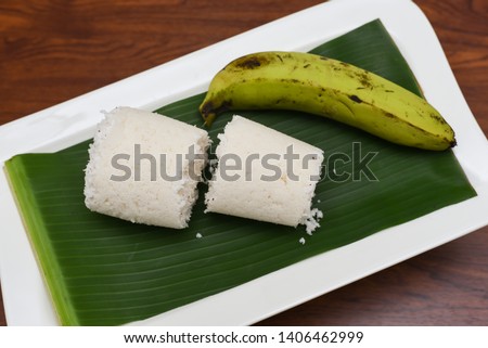 Popular South Indian steamed breakfast Puttu or Pittu made of rice flour and grated coconut  in the bamboo mould with banana Kerala, India. Sri lankan food served in banana leaf.