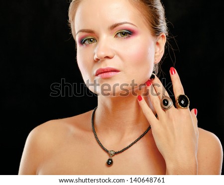 Portrait of pretty young woman with beads and rings on a hand, isolated on black background