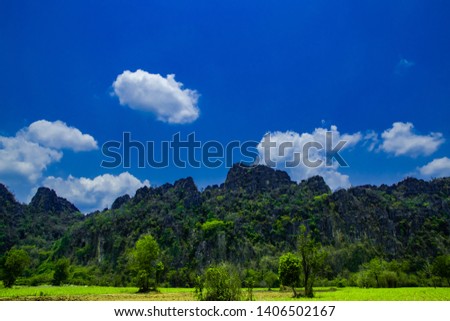 Stone Mountain View and beautiful blue sky and white cloudy background over the green field in countryside landscape of Thailand, at Banmung  ,NoenMaPrang Pitsanulok province. 