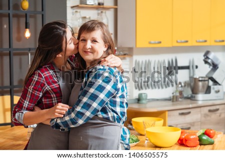 Home family leisure. Mother and daughter cooking together in modern kitchen. Ladies sharing love and care.