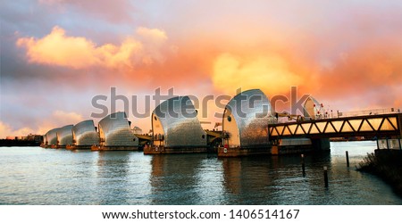 Thames Barrier, tidal protector, over dramatic sunset, commissioned by the Greater London Council, was complete by 1982, the world's second largest movable flood barrier. Royalty-Free Stock Photo #1406514167