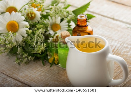 Essential aroma oil with wild flowers  on wooden background. Selective focus.