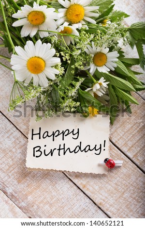 Post card with wild flowers and card with words Happy Birthday on it.