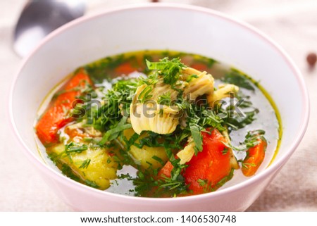 homemade soup with chicken and vegetables with lots of greens. closeup