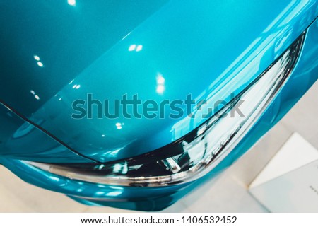 Close up of headlight detail of modern luxury car with projector lens for low and high beam. Front view of sport crossover vehicle head lamp. Concept of car detailing and light technology background.