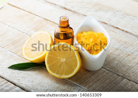 Essential aroma oil and sea salt with lemon on wooden background. Selective focus.