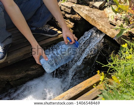 pours water into a bottle from stream with clean drinking water.