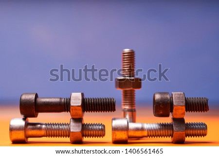 Bolted connecting elements on orange, blue background close-up.