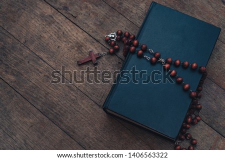 Old red Beads and crucifix on a Holy Bible background. 